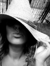 Close-up of beautiful young woman puckering while wearing hat