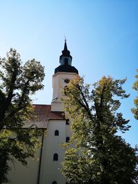 Low angle view of trees and building against sky