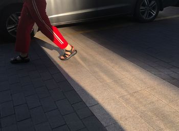 Low section of woman with high heels walking on sidewalk in city