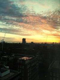 Cityscape against cloudy sky at sunset