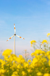 Wind turbines on field against sky