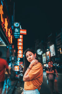 Woman standing on illuminated city street at night