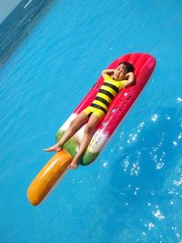 High angle view of boy lying over inflatable raft in swimming pool