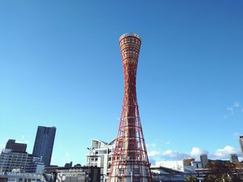 Low angle view of crane by building against sky