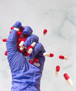 Cropped hand of person holding medicines against white background