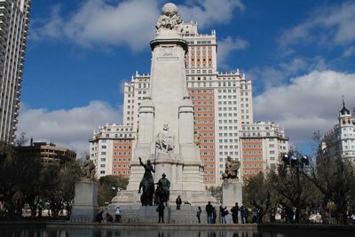 People at miguel de cervantes monument in plaza de espana against edificio espana