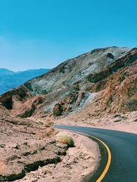 Scenic view of mountain road against clear blue sky