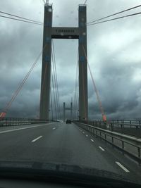 Suspension bridge against cloudy sky