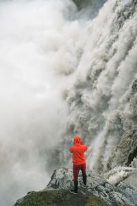 Rear view of man standing on rock against sky