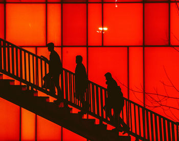 Silhouette people walking on staircase at night