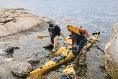 High angle view of men putting kayaks on coast