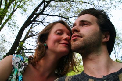 Portrait of smiling woman with boyfriend against trees