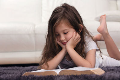 Cute girl reading book at home