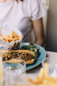 Midsection of woman having comfort food, specifically a hot dog 