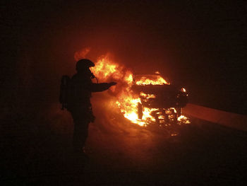 Man standing by bonfire at night