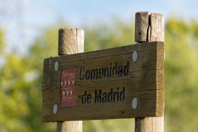 Close-up of signboard on wooden fence