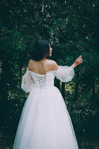 Rear view of woman standing against trees