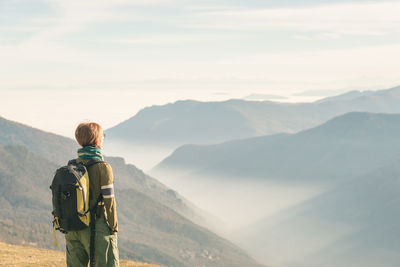 Rear view of man standing on mountain against sky