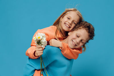 Portrait of young woman holding gift against blue background