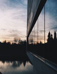 Silhouette bridge over lake against sky during sunset