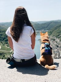 Rear view of woman with dog sitting outdoors