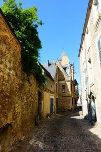 Footpath amidst buildings against blue sky