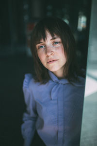 Woman looking away while standing by wall