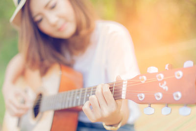 Young woman playing guitar on grassy field at park