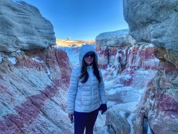 Portrait of woman standing on rock against sky