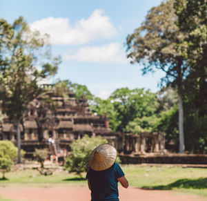 Man in asian style conical hat walking against temple