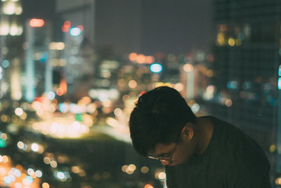 Portrait of man in illuminated city at night