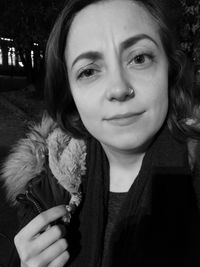 Close-up portrait of young woman in warm clothing standing outdoors at night
