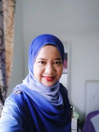 Portrait of smiling young woman wearing hijab at home