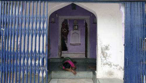 Woman leaning on door of building