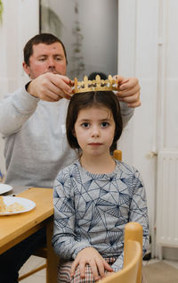 A young man puts a crown on a girl after eating a royal galette.