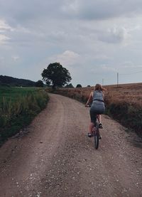 Rear view of person riding bicycle on road