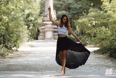 Full length portrait of young woman standing on road