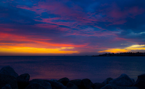 Scenic view of sea against dramatic sky during sunset