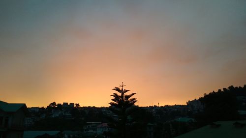 Silhouette trees and buildings against sky during sunset