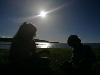 Rear view of silhouette couple overlooking calm sea