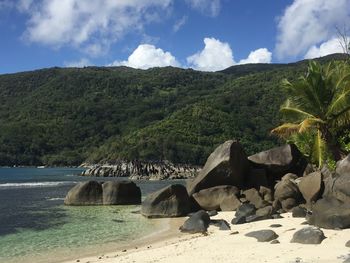 Scenic view of rocks by sea against sky