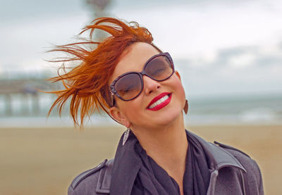 Portrait of smiling young woman wearing sunglasses against sky