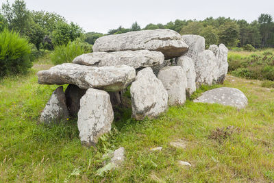 Stone wall by rocks on field