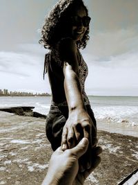 Low section of woman on beach against sky