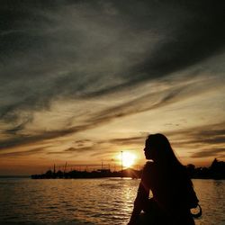 Silhouette of people in water at sunset