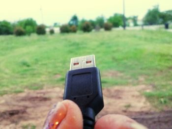 Close-up of hand holding camera on grassy field