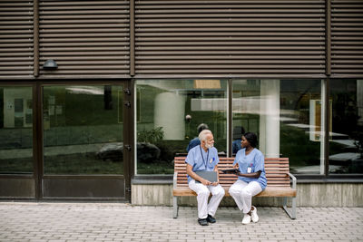 Senior nurse talking to female colleague while sitting on bench