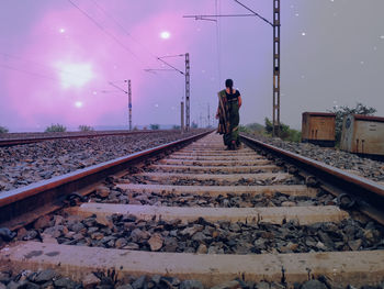 Rear view of man on railroad track against sky