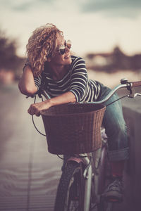 Woman looking away while standing with bicycle outdoors