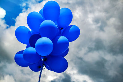 Blue balloons on cloudy sky